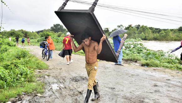 Pobladores transportan sus pertenencias luego de que el gobierno emitiera alerta roja y ordenara evacuar las zonas bajas de la costa norte de Honduras debido al aumento de las lluvias por causa del huracán Julia. (EFE/José Valle).