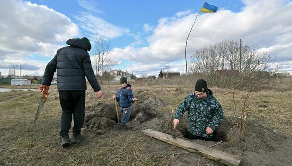 Niños cavan trincheras mientras juegan en las afueras de la ciudad de Borodyanka, región de Kiev, para evitar que el ejército ruso vuelva a ocupar la ciudad el 6 de marzo de 2023. (Foto de Sergei SUPINSKY / AFP)