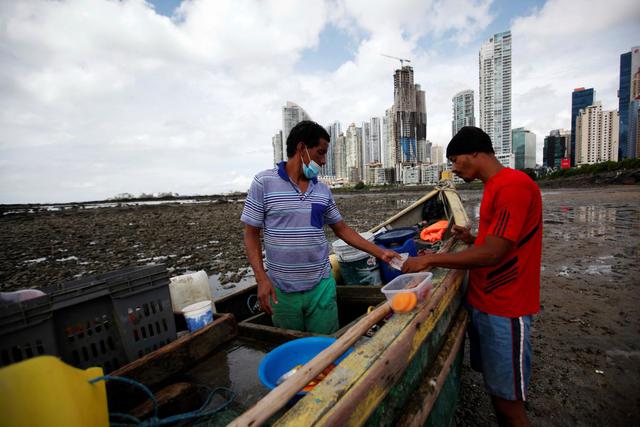 Pescadores trabajan frente al complejo de Punta Pacífica en el puerto pesquero de Boca La Caja, en Ciudad de Panamá, en medio de la pandemia de coronavirus. (EFE/ Bienvenido Velasco).