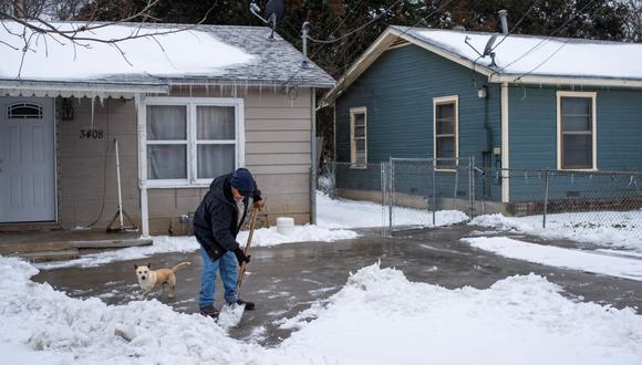 Un residente de Waco, Texas, limpia la nieve de su camino de entrada junto con su perro el 17 de febrero de 2021. (Foto fererencial, MATTHEW BUSCH / AFP).
