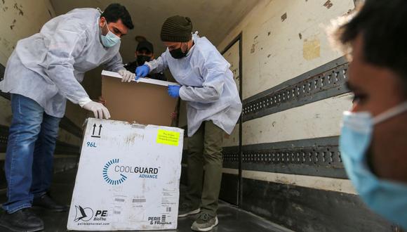 Trabajadores palestinos descargan el primer cargamento de vacunas contra el coronavirus (COVID-19) en el sur de la Franja de Gaza, el 17 de febrero de 2021. (REUTERS/Ibraheem Abu Mustafa).