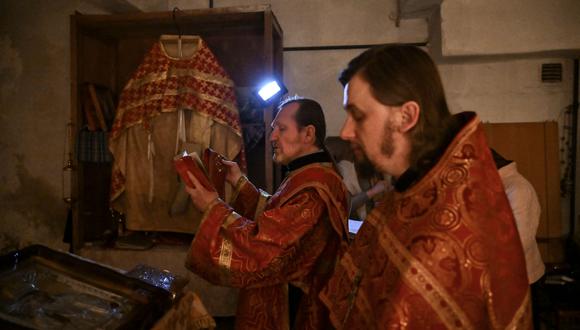 Sacerdotes ortodoxos rezan con los residentes en una iglesia subterránea improvisada en Lysychans'k, en la región oriental de Ucrania de Donbas, a fines del 20 de mayo de 2022.