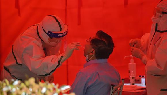 Un trabajador médico toma una muestra de un hisopo de un hombre para realizar una prueba del coronavirus COVID-19 en Wuhan, en la provincia central de Hubei, en China, el 19 de mayo de 2020. (Foto de Hector RETAMAL / AFP).