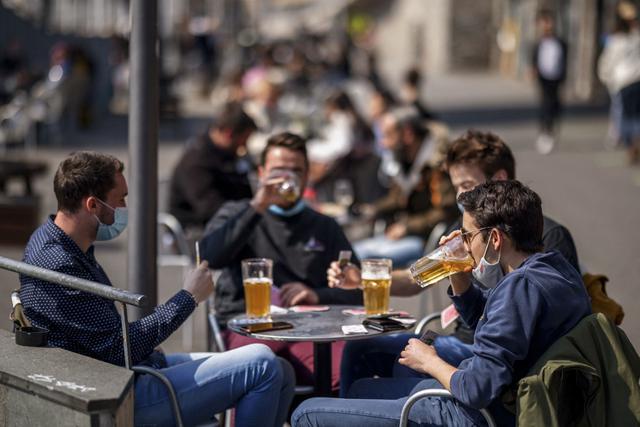 La gente disfruta de una cerveza y juega a las cartas cuando las terrazas de bares reabrieron en Lausana, el 19 de abril de 2021, luego de que el Gobierno de Suiza aliviara significativamente sus restricciones de COVID-19 a pesar de reconocer que la situación del virus del país "sigue siendo frágil" e incluso ha empeorado recientemente. (Foto de Valentín FLAURAUD / AFP)