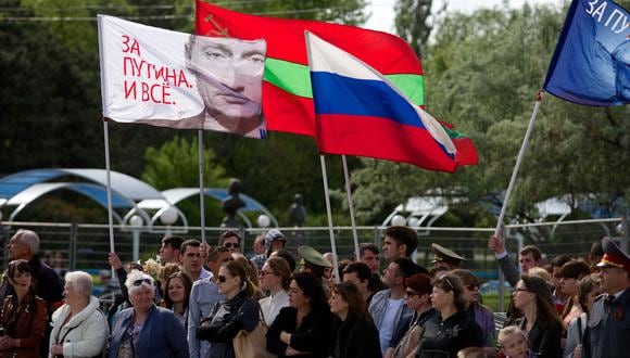 La gente porta una bandera rusa (C) y una bandera con un retrato del presidente ruso Vladimir Putin que dice "¡Estamos a favor de Putin!" en Tiraspol, la ciudad principal de la región separatista de Transnistria en Moldavia, el 9 de mayo de 2014. (Foto de VADIM DENISOV / AFP / ARCHIVO).