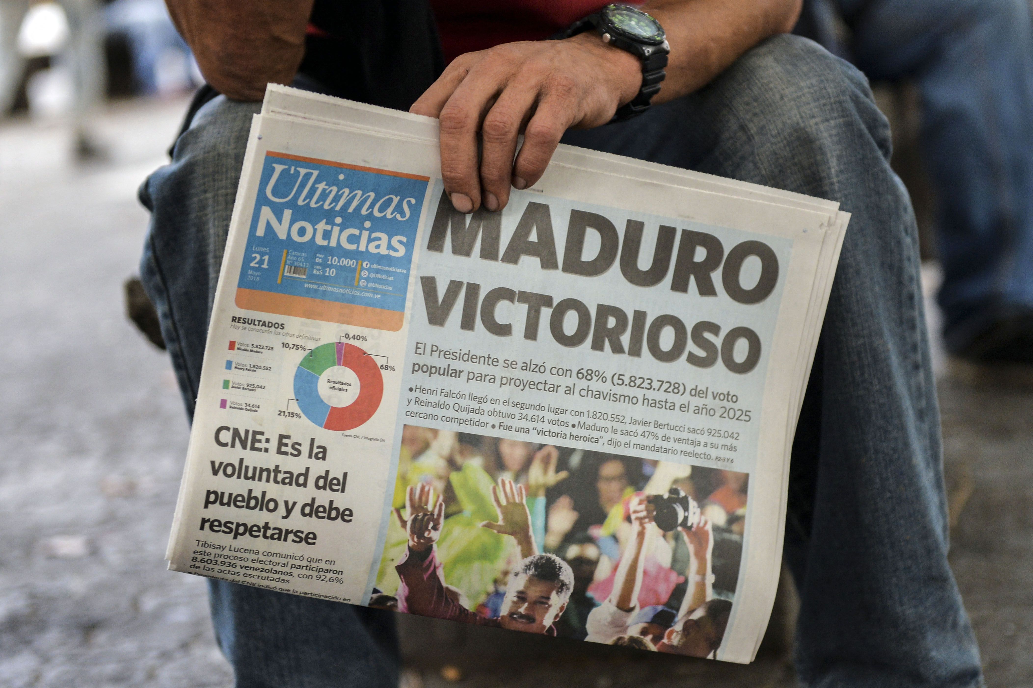 A man holds a newspaper that refers to the victory of re-elected president Nicolás Maduro in the Venezuelan presidential elections in Caracas, on May 21, 2018. (Photo by Luis ROBAYO/AFP).
