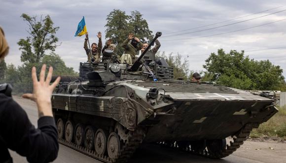 En esta fotografía tomada el 20 de septiembre de 2022, un residente local saluda a los soldados de Ucrania que viajan en un vehículo blindado en Mala Komyshuvakha, cerca de Izyum, región de Kharkiv. (Yevhen TITOV / AFP).
