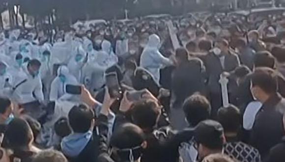 Esta captura de imagen tomada de un video de AFP y publicada el 23 de noviembre de 2022 muestra a los trabajadores de la fábrica de iPhone de Foxconn en Zhengzhou, en el centro de China, enfrentándose a la policía. (AFP).