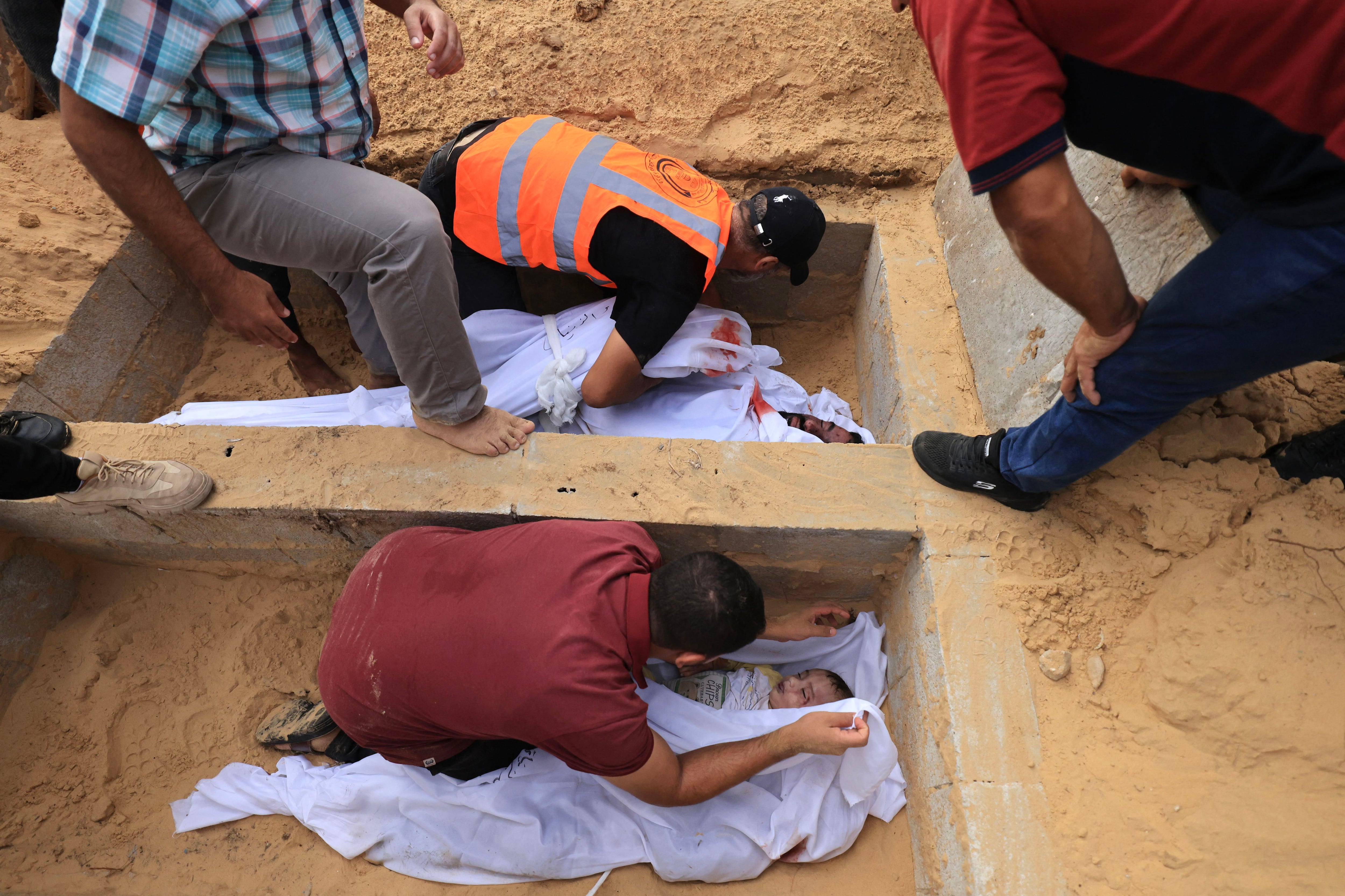 Members of the al-Zanati family killed after an Israeli attack are buried in Khan Yunis on October 23, 2023. (Photo by Mahmud JAMONES/AFP).