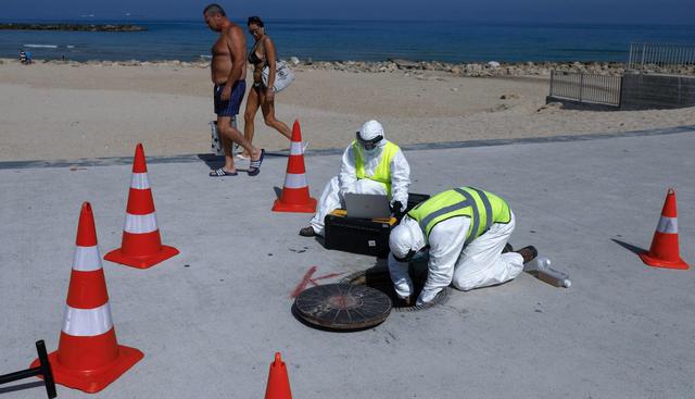 Técnicos de la firma israelí Kando extraen muestras de aguas residuales en la ciudad costera de Ascalón, que busca rastrear al coronavirus y prevenir la aparición de nuevos focos infecciosos. (AFP / MENAHEM KAHANA).