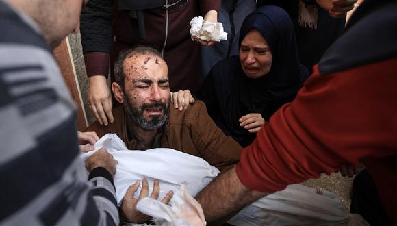Familiares reaccionan mientras el hombre herido sostiene el cuerpo de uno de los dos hijos de la pareja que murieron en el bombardeo israelí, en Khan Yunis, en el sur de la Franja de Gaza, el 19 de noviembre de 2023. (Foto de MAHMUD HAMS / AFP)
