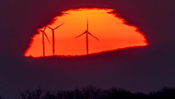 Turbinas eólicas frente al Sol, que sale por el horizonte en Fráncfort, Alemania.