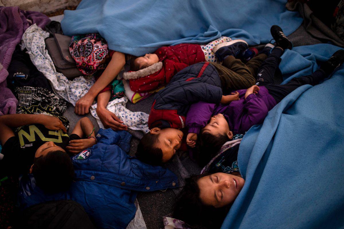 Las personas duermen en el suelo mientras pasan la noche en una carretera cerca de Mitilene después de que un incendio destruyera el campo de refugiados de Moria, el más grande de Grecia, en la isla de Lesbos. (AFP / ANGELOS TZORTZINIS).