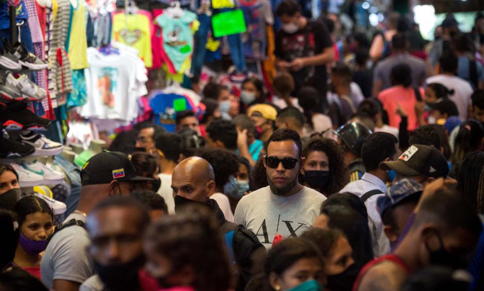 Un hombre usando de forma inapropiada una mascarilla camina entre una multitud en el mercado de La Hoyada en Caracas,  en medio de la nueva pandemia de coronavirus. (Foto: CRISTIAN HERNANDEZ / AFP)