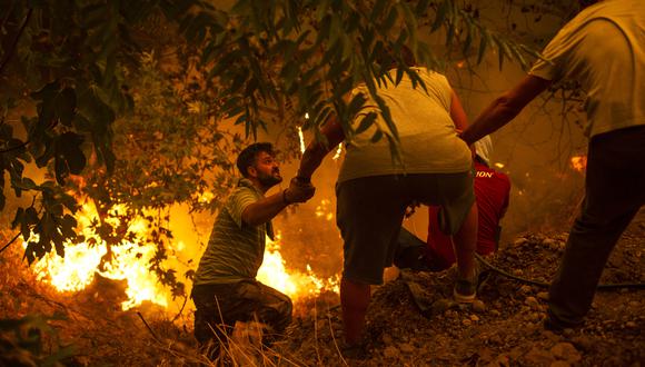Los residentes locales luchan contra el incendio forestal en el pueblo de Gouves en la isla de Evia (Eubea), en Grecia. (Foto: ANGELOS TZORTZINIS / AFP)
