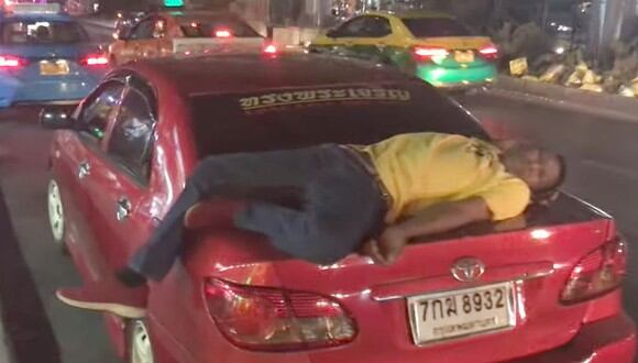 Un taxista se quedó dormido sobre la maletera de su vehículo en plena carretera en Bangkok, Tailandia | Foto: Captura de video YouTube / Viral Press