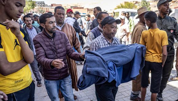 Un hombre lleva el cuerpo envuelto en una manta de una víctima que murió en un terremoto en Moulay Brahim, provincia de Al Haouz, el 9 de septiembre de 2023. (Foto de FADEL SENNA / AFP)