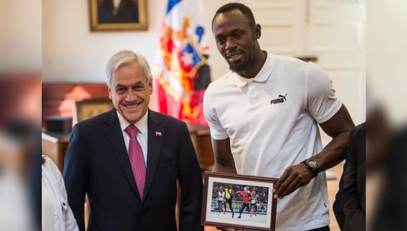 Usain Bolt posa junto al mandatario Sebastián Piñera y su curioso obsequio. (Foto: AFP)