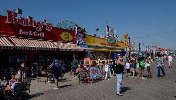 La gente camina en el paseo marítimo de la playa de Coney Island mientras se levantan las restricciones por coronavirus en Nueva York el 19 de mayo de 2021.
(Angela Weiss / AFP).