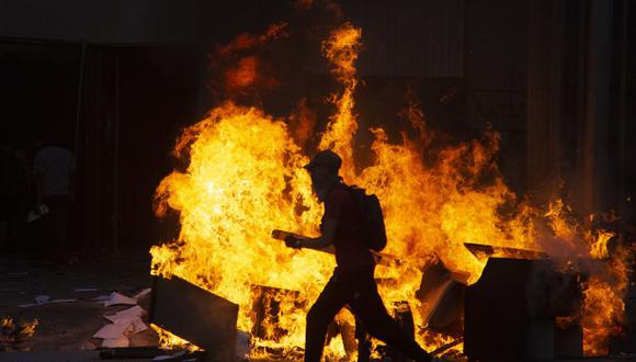 Un manifestante es visto junto a una hoguera durante los enfrentamientos con la policía antidisturbios en la conmemoración del primer aniversario del levantamiento social en Chile. (Foto de CLAUDIO REYES / AFP).