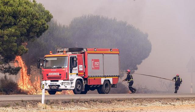 GRA206. MAZAG”N (HUELVA), 25/06/2017.- Bomberos intentan apagar un nuevo foco de fuego en la carretera que une las localidades de MazagÛn y MatalascaÒas, en Huelva, en el incendio declarado ayer en el tÈrmino municipal de Moguer que ha obligado a desalojar a m·s de 2.000 personas y que contin˙a acechando el Espacio Natural de DoÒana. EFE/Juli·n PÈrez