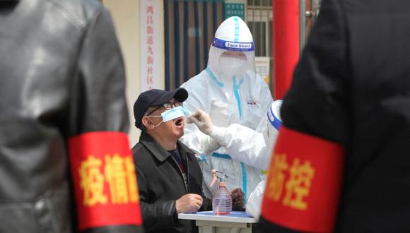 Un trabajador médico con un traje protector recolecta una muestra de hisopo de un residente para la prueba de ácido nucleico durante una prueba masiva de la enfermedad por coronavirus (COVID-19), en un complejo residencial en Jiaozuo, provincia de Henan, China. (Foto: China Daily vía REUTERS).
