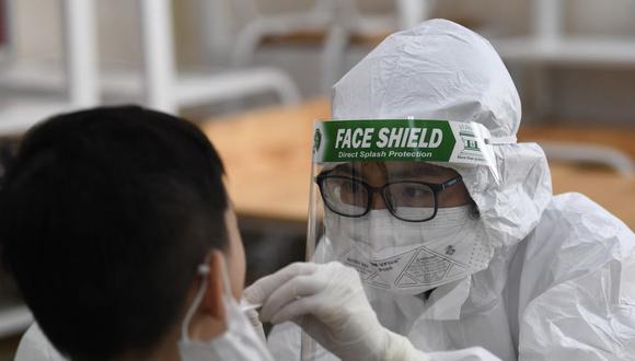 Un trabajador de la salud que usa equipo de protección personal (EPP) realiza una prueba de coronavirus en un estudiante en la escuela privada Vinschool, en Hanoi (Vietnam), el 22 de mayo de 2021. (Nhac NGUYEN / AFP).