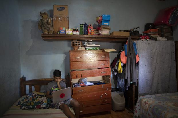 Samuel Andrés Mendoza está sentado en su habitación con una computadora portátil, que le regalaron sus seguidores en las redes sociales, en su casa en Barquisimeto, Venezuela, el martes 2 de marzo de 2021. (AP Foto/Ariana Cubillos).