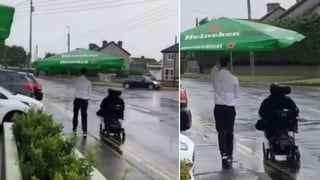 Camarero conmueve al proteger de un aguacero a un cliente en silla de ruedas