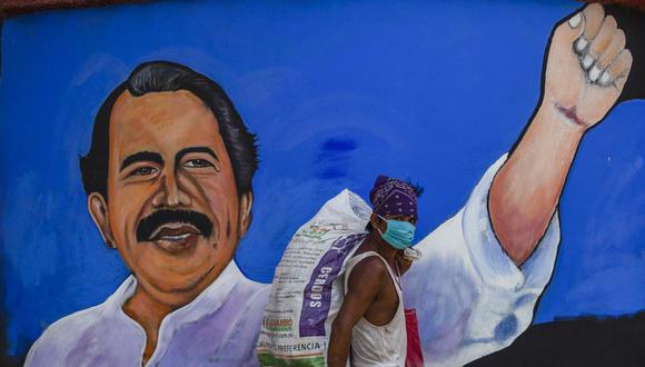 Un indigente que usa mascarilla pasa frente a un mural que representa al presidente de Nicaragua, Daniel Ortega, en Managua el 9 de abril de 2020. (Foto de INTI OCON / AFP).