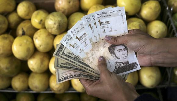 Un vendedor de frutas muestra bolívares venezolanos y billetes de dólares estadounidenses en el Mercado Municipal de Chacao, en Caracas.