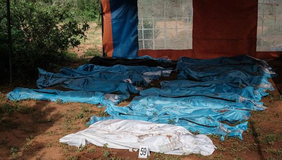 Los cuerpos exhumados en bolsas para cadáveres se muestran en el suelo antes de ser transportados a la morgue, en la fosa común de Shakahola, en las afueras de la ciudad costera de Malindi, el 25 de abril de 2023. (Foto de Yasuyoshi CHIBA / AFP)
