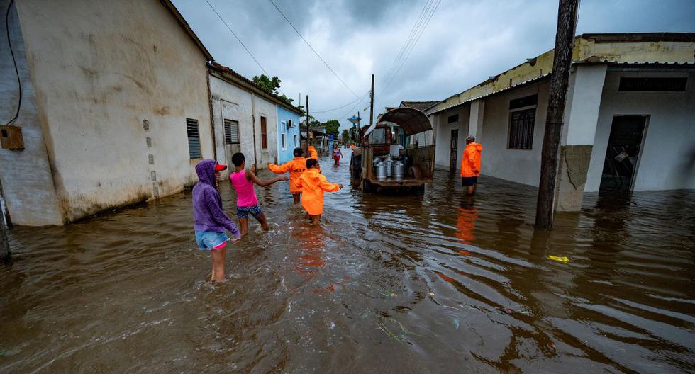 La gente camina por una calle inundada en Batabano, Cuba, el 27 de septiembre de 2022, durante el paso del huracán Ian.
(YAMIL LAGE / AFP).