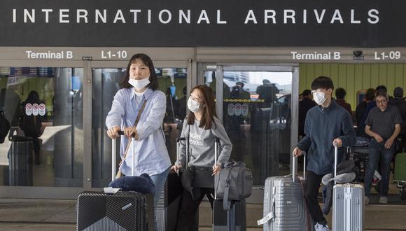 Pasajeros usan máscaras faciales para protegerse contra la propagación del coronavirus cuando llegan en un vuelo desde Asia, al Aeropuerto Internacional de Los Ángeles, California, el 2 de febrero de 2020. (Foto referencial de Mark RALSTON / AFP)