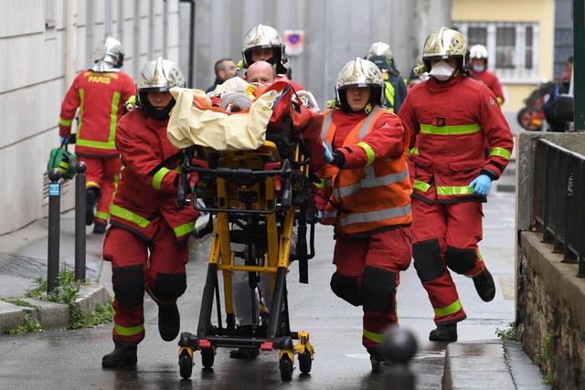 Bomberos franceses empujan una camilla con un herido cerca de las antiguas oficinas de la revista satírica francesa Charlie Hebdo en París. (AFP / Alain JOCARD).