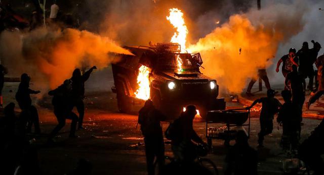 Manifestantes queman un vehículo de la policía antidisturbios durante los enfrentamientos tras una protesta contra el gobierno del presidente chileno Sebastián Piñera en Santiago. (AFP / JAVIER TORRES).