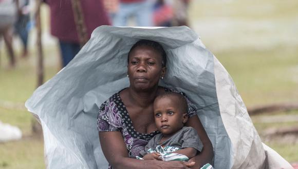 Una damnificada por el terremoto en Haití y su hijo se protegen como pueden de la tormenta tropical Grace cerca de Les Cayes. (REGINALD LOUISSAINT JR / AFP).