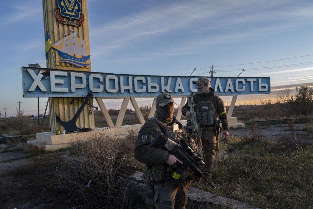 Two members of the Ukrainian defense forces stand next to a banner that reads 