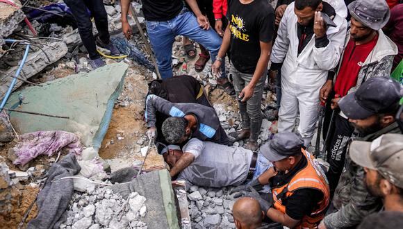 La gente se reúne mientras los voluntarios intentan rescatar a los sobrevivientes y recuperar los cuerpos de las víctimas de debajo de los escombros de un edificio derrumbado después del bombardeo israelí en Nuseirat, en el centro de la Franja de Gaza, el 14 de mayo de 2024, en medio de la actual Conflicto en territorio palestino entre Israel y Hamás. (Foto de AFP)