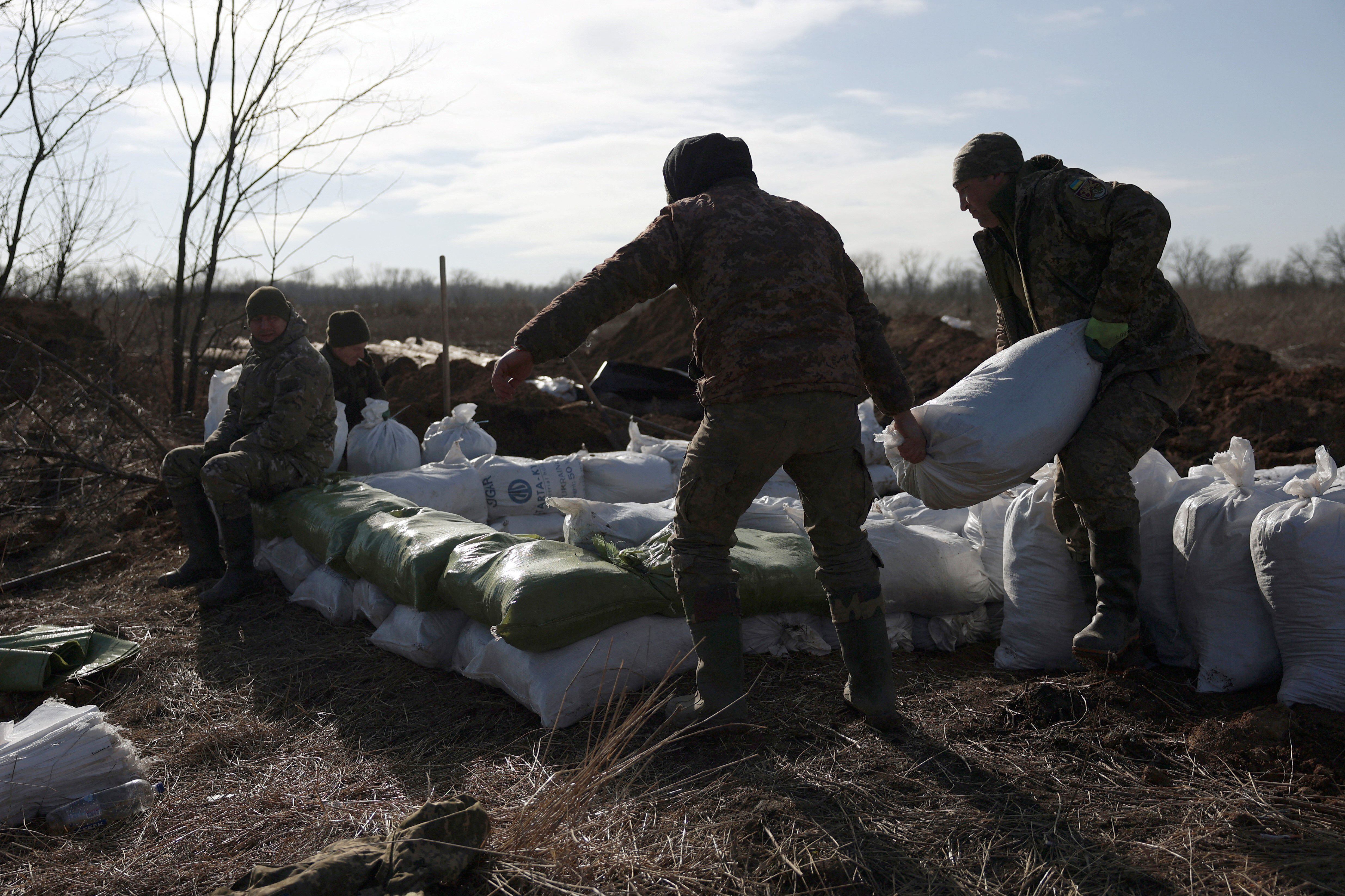 Ukrainian military personnel pile up bags of earth to build a fortification not far from the city of Avdiivka, Donetsk region, on February 17, 2024. (Photo by Anatolii STEPANOV/AFP).