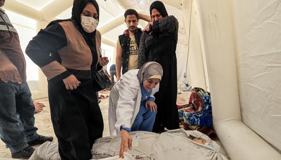La gente inspecciona para identificar uno de los cuerpos de las víctimas del ataque nocturno en el hospital árabe Ahli en el centro de Gaza, el 18 de octubre de 2023. (Foto de AFP).