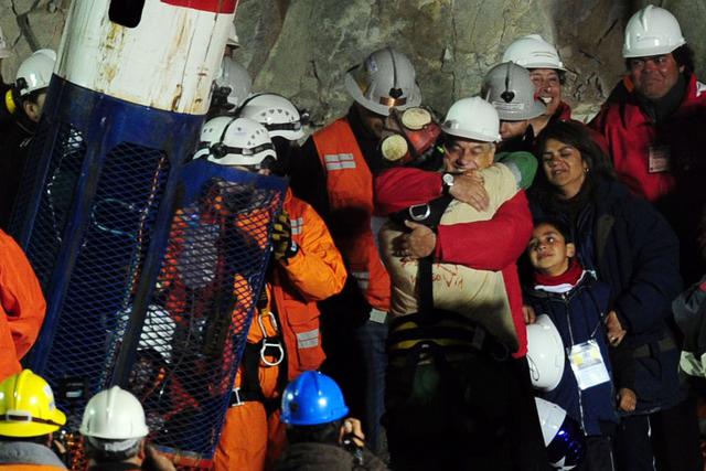 En esta foto de archivo tomada el 12 de octubre de 2010, el minero chileno Florencio Avalos (centro, con traje beige) abraza al presidente Sebastián Piñera, segundos después de salir de la cápsula Fenix. (AFP / Martín BERNETTI).