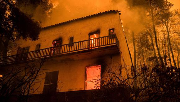 Una casa se quema durante el incendio que se acerca al pueblo de Pefki, en la isla de Evia (Eubea), la segunda isla más grande de Grecia, el 8 de agosto de 2021.(Foto de ANGELOS TZORTZINIS / AFP).