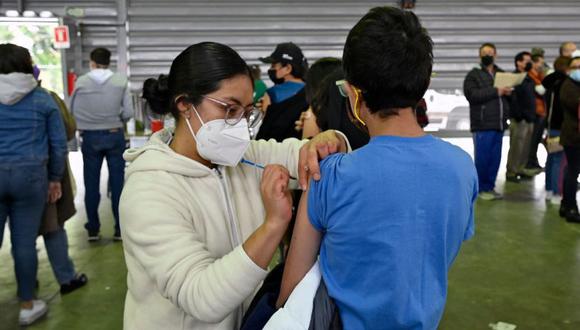 Un adolescente es inoculado con la vacuna Pfizer-BioNTech contra la enfermedad del nuevo coronavirus, mientras jóvenes de entre 15 y 17 años comenzaron a recibir la primera dosis, en el Palacio de Deportes de la Ciudad de México. (Foto: Alfredo ESTRELLA/AFP)
