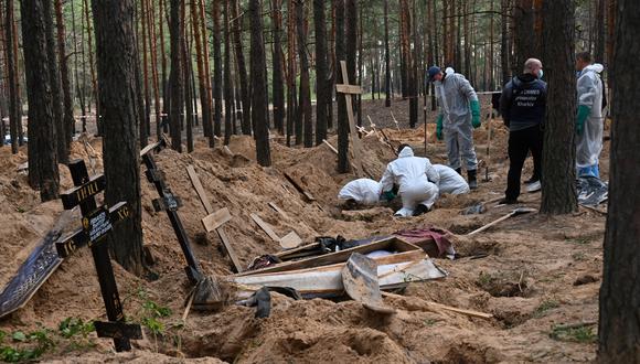 Los forenses desentierran un cuerpo en un bosque cerca de Izyum, en el este de Ucrania, el 19 de septiembre de 2022, donde los investigadores ucranianos descubrieron más de 440 tumbas después de que la ciudad fuera recuperada de manos de los rusos, trayendo nuevos reclamos de atrocidades cometidas por los rusos. (Foto de SERGEY BOBOK / AFP)