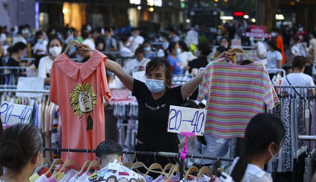 Un vendedor ambulante con una máscara contra el coronavirus es visto ofreciendo sus productos en un mercado al aire libre en una calle en Wuhan (China). Fotografía del 8 de junio de 2020. (STR / AFP).