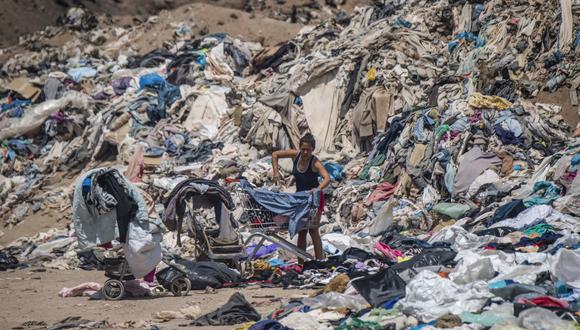 En esta foto de archivo tomada el 26 de septiembre de 2021, una mujer busca ropa usada entre toneladas desechadas en el desierto de Atacama, en Alto Hospicio, Iquique, Chile. (Foto: Martin BERNETTI / AFP)