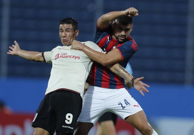 Striker Jonathan Dos Santos of Peru's Universitario, left, fights for the ball with midfielder Victor Caceres of Paraguay's Cerro Porteno during a Copa Libertadores soccer match at the Pablo Rojas stadium in Asuncion, Paraguay, Wednesday, Feb. 12, 2020. (AP Photo/Jorge Saenz)