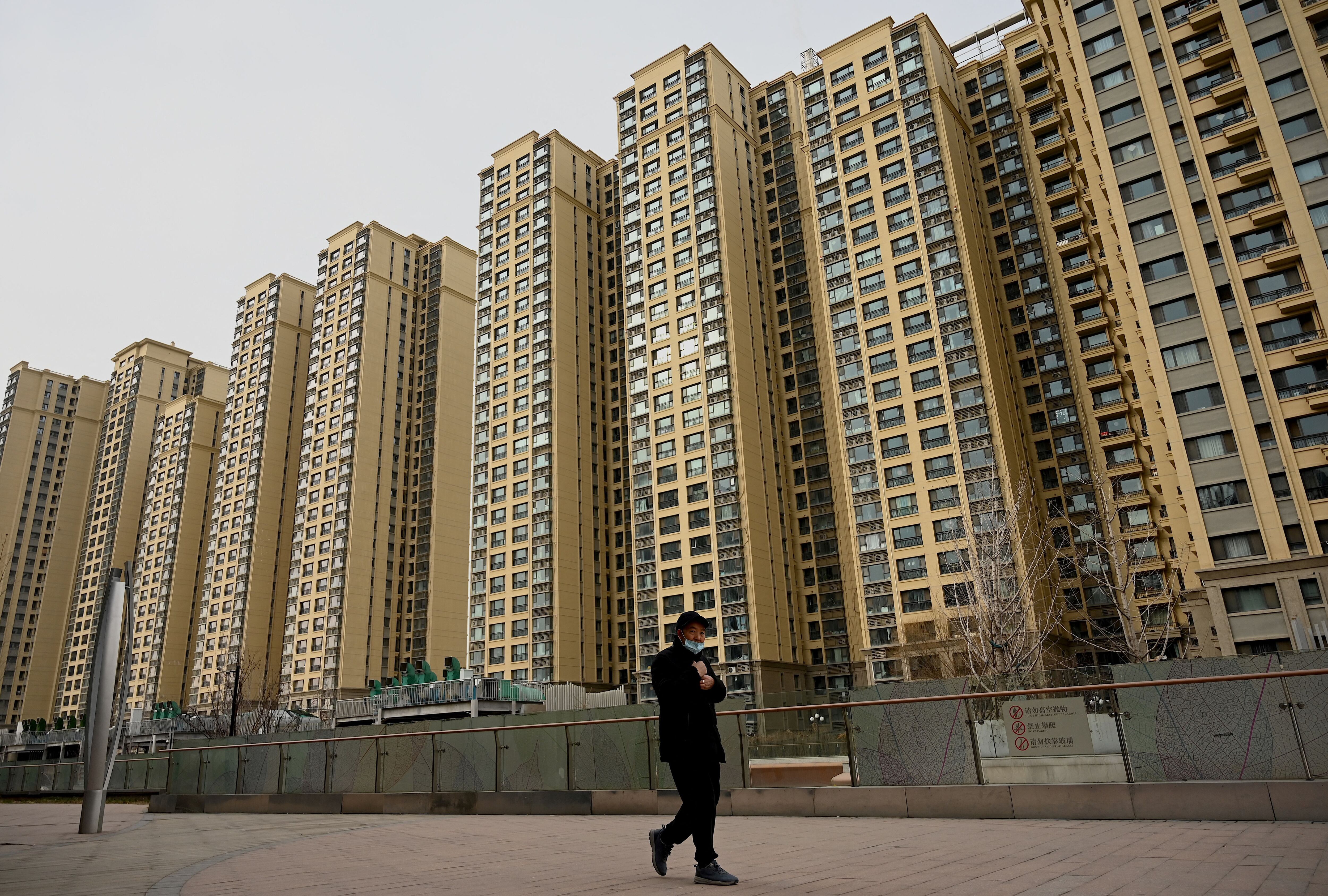 A man walks past a housing complex owned by Chinese real estate developer Evergrande in Beijing, on December 8, 2021. (Photo by Noel Celis/AFP).