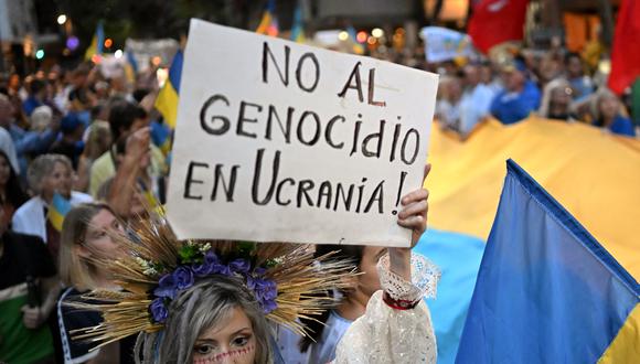 Una mujer sostiene un cartel que dice "¡No al genocidio en Ucrania!" durante una protesta frente a la embajada rusa en Buenos Aires, el 24 de febrero de 2023, en el primer aniversario de la invasión rusa a Ucrania. (Foto por Luis ROBAYO / AFP)